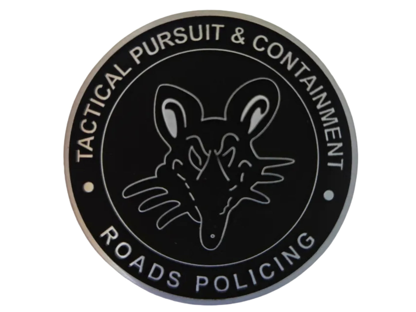 A circular black and silver badge or emblem featuring a stylized fox head in the center, with the text 'TACTICAL PURSUIT & CONTAINMENT' and 'ROADS POLICING' in white lettering, shown on a plain light background.